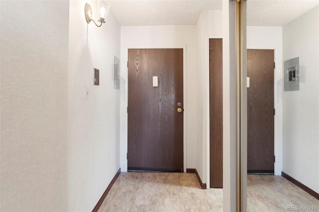 corridor with a textured ceiling, electric panel, and baseboards