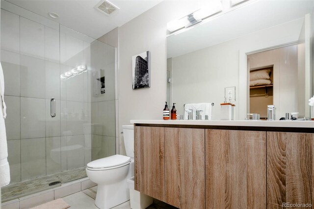 bathroom featuring tile patterned floors, vanity, toilet, and a shower with shower door