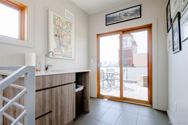 doorway to outside featuring a wealth of natural light, sink, and light tile patterned flooring