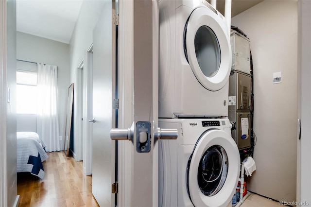 washroom with light hardwood / wood-style flooring and stacked washer and clothes dryer