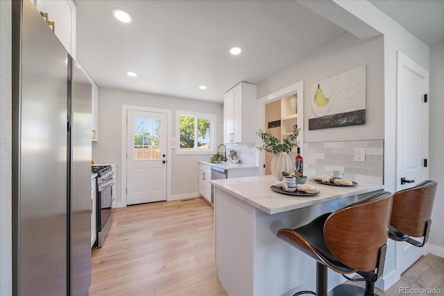 3216 Elizabeth, Denver, CO 80205 - kitchen featuring appliances with stainless steel finishes, white cabinets, backsplash, light wood-style flooring, and a sink
