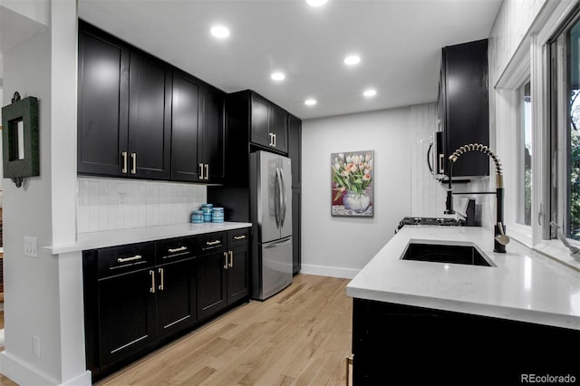 8413 E Jamison Cir, Englewood, CO 80112 - kitchen featuring dark cabinets, freestanding refrigerator, tasteful backsplash, light wood-style floors, and light countertops