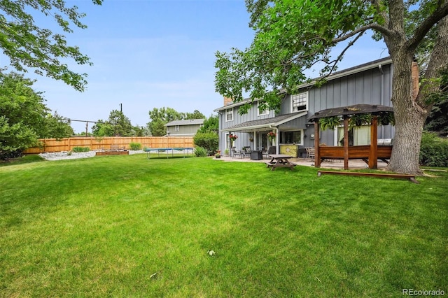 8413 E Jamison Cir, Englewood, CO 80112 - rear view of property with board and batten siding, a fenced backyard, a patio area, a trampoline, and a chimney