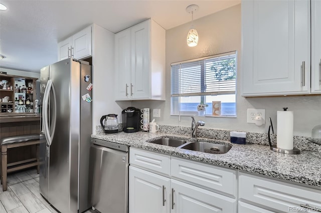 kitchen with white cabinetry, light stone countertops, sink, decorative light fixtures, and stainless steel appliances