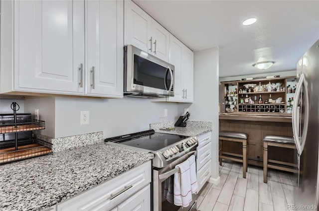 kitchen with light stone countertops, appliances with stainless steel finishes, and white cabinets