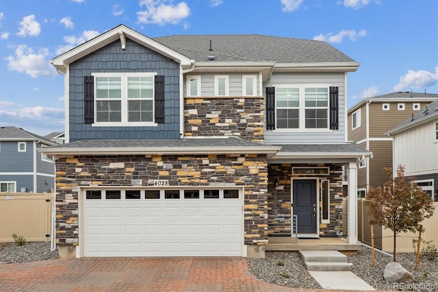 view of front of house featuring fence, stone siding, decorative driveway, roof with shingles, and an attached garage