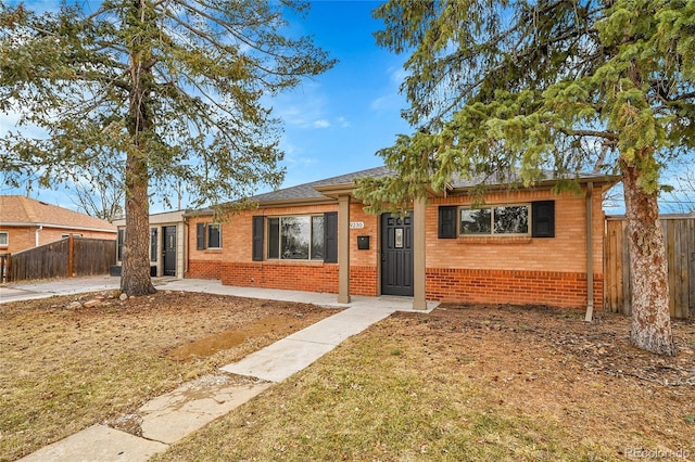 single story home with fence, brick siding, and a front lawn