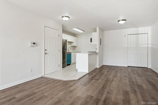 kitchen with wood finished floors, open floor plan, white cabinetry, freestanding refrigerator, and dishwasher