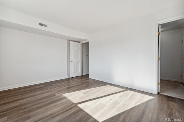 empty room with visible vents, baseboards, and wood finished floors