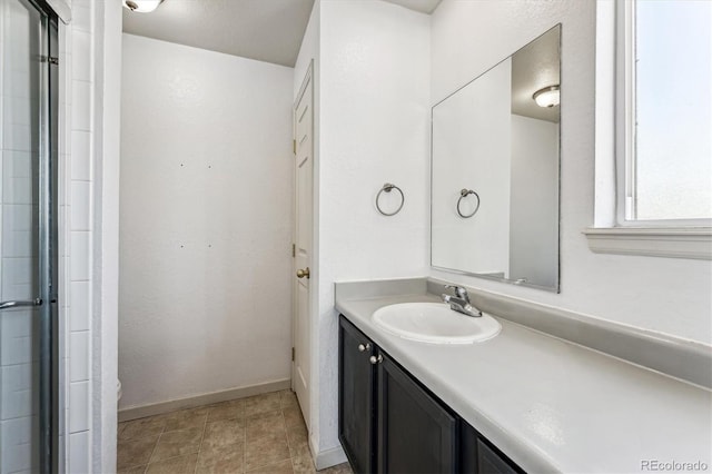 bathroom with vanity, baseboards, and a shower with shower door