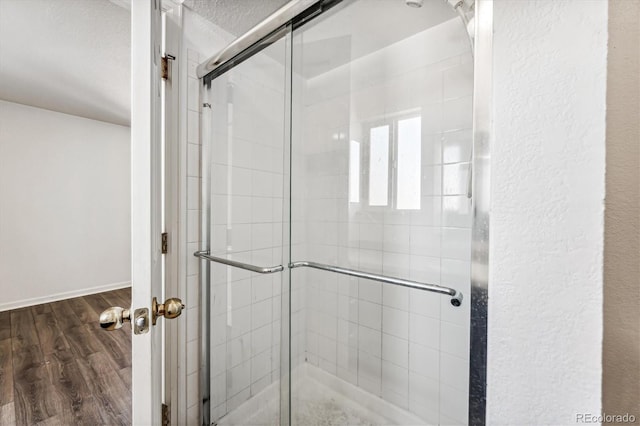 full bathroom with a shower stall, wood finished floors, and a textured ceiling