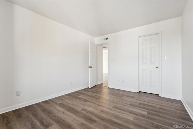 unfurnished bedroom featuring visible vents, dark wood-style floors, and baseboards