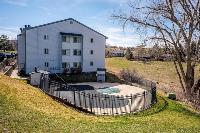 rear view of property featuring a patio, a yard, fence, and a fenced in pool