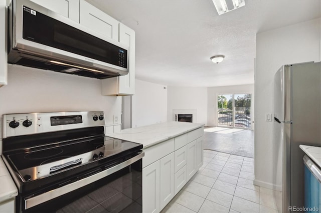 kitchen with white cabinets, a fireplace, open floor plan, and stainless steel appliances