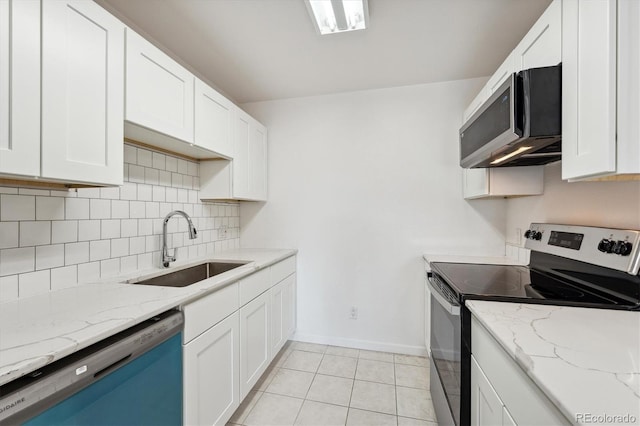 kitchen featuring light tile patterned floors, a sink, decorative backsplash, appliances with stainless steel finishes, and white cabinetry