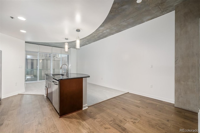 kitchen with a kitchen island with sink, light hardwood / wood-style flooring, hanging light fixtures, and sink