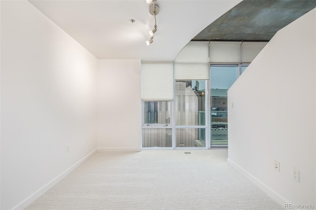 empty room with rail lighting, carpet floors, and floor to ceiling windows