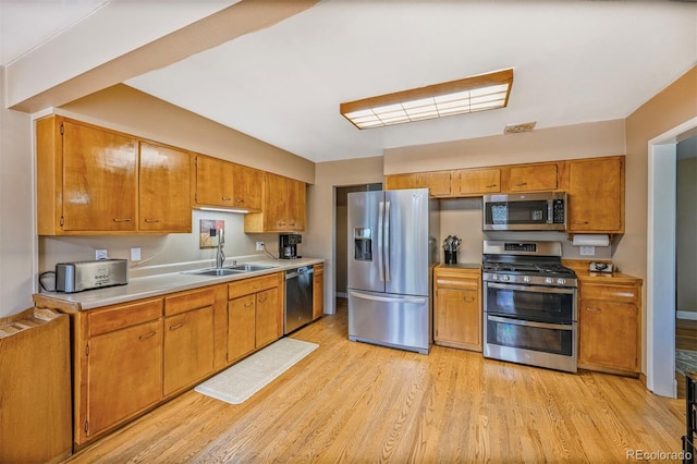 kitchen featuring a sink, brown cabinetry, light wood-type flooring, light countertops, and appliances with stainless steel finishes