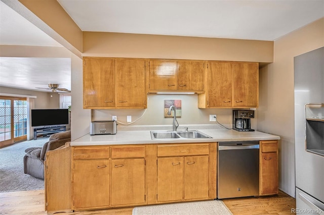 kitchen with a sink, light wood finished floors, light countertops, a ceiling fan, and appliances with stainless steel finishes