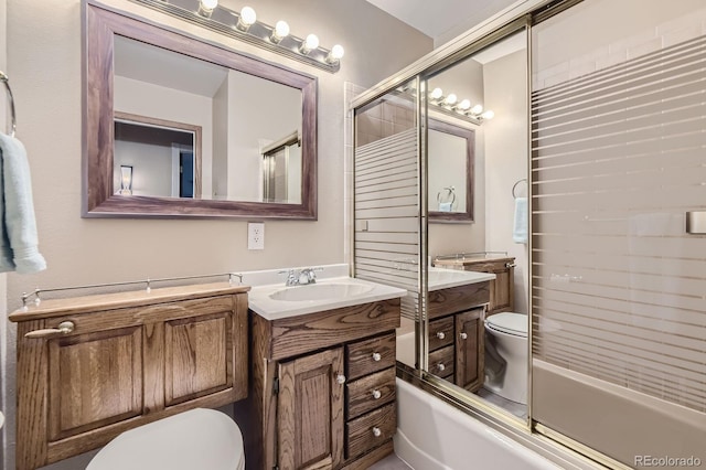 bathroom with toilet, vanity, and combined bath / shower with glass door