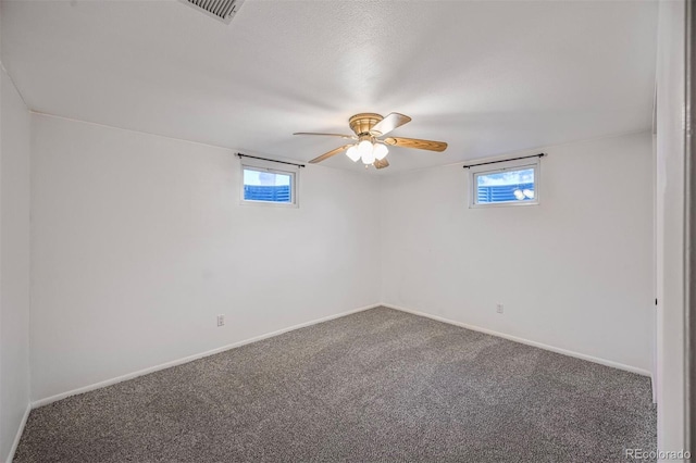 carpeted spare room featuring plenty of natural light, visible vents, and baseboards