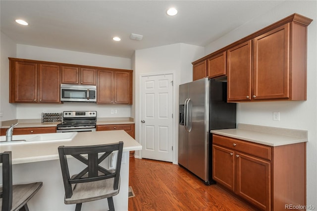 6434 N Ensenada Ct, Aurora, CO 80019 - kitchen with appliances with stainless steel finishes, light countertops, recessed lighting, wood finished floors, and a kitchen bar