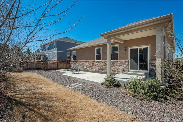 6434 N Ensenada Ct, Aurora, CO 80019 - rear view of house with a patio, fence, and stone siding