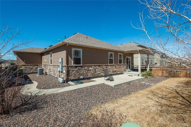 6434 N Ensenada Ct, Aurora, CO 80019 - back of house with roof with shingles, central AC, fence, a patio, and stone siding