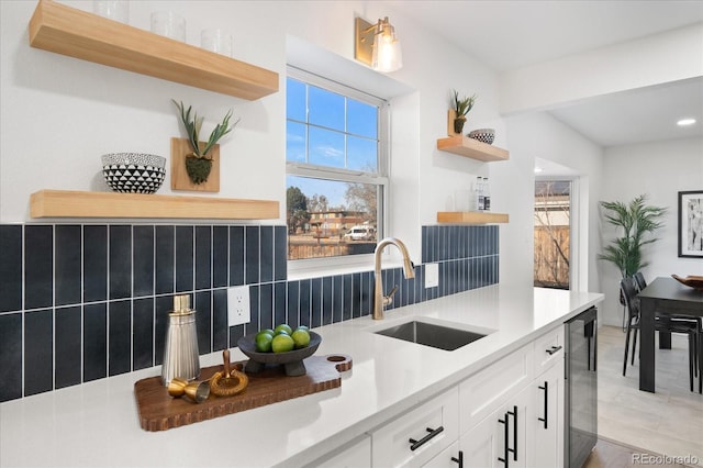 kitchen with backsplash, white cabinetry, and sink