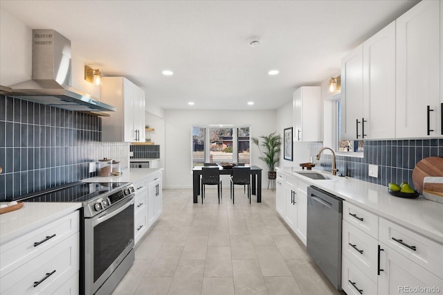 kitchen with wall chimney exhaust hood, white cabinetry, and appliances with stainless steel finishes