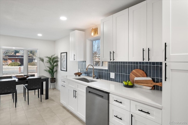 kitchen featuring tasteful backsplash, sink, light tile patterned floors, dishwasher, and white cabinetry