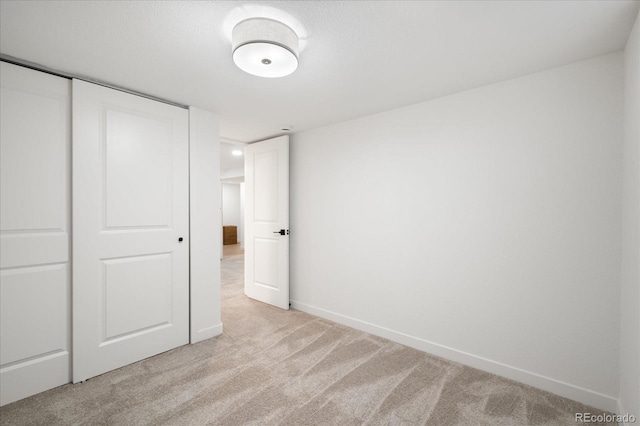 unfurnished bedroom featuring light carpet and a closet