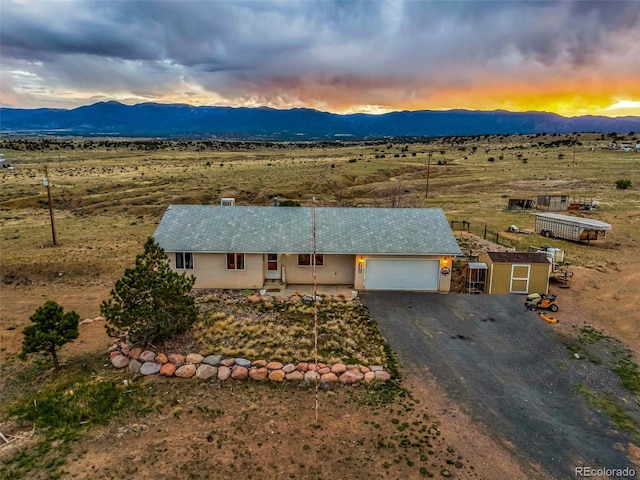 3569 County Road 19, Florence, CO 81226 - view of front of home featuring a mountain view, a garage, asphalt driveway, a rural view, and fence