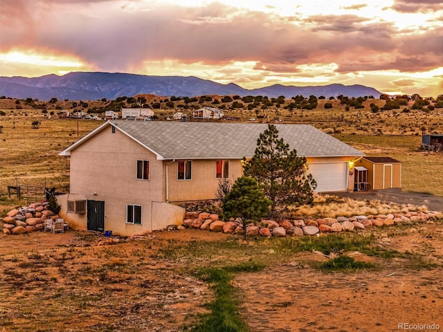 3569 County Road 19, Florence, CO 81226 - view of front of property with a mountain view, stucco siding, roof with shingles, an outbuilding, and a garage