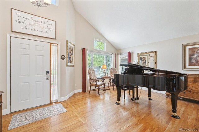 foyer entrance featuring baseboards, high vaulted ceiling, and light wood-style flooring