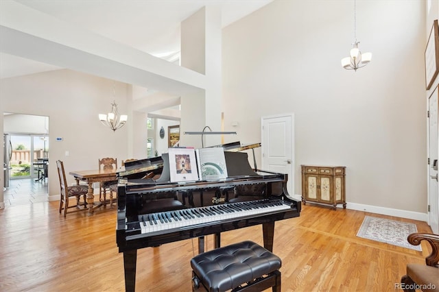 sitting room featuring an inviting chandelier, high vaulted ceiling, baseboards, and light wood-style flooring