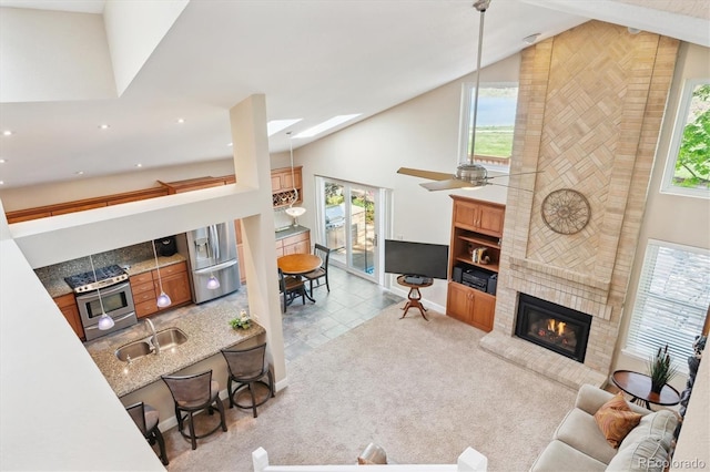 tiled living room with a sink, a brick fireplace, a healthy amount of sunlight, and high vaulted ceiling