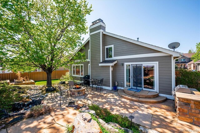 back of property featuring a fire pit, fence, a patio, a chimney, and area for grilling