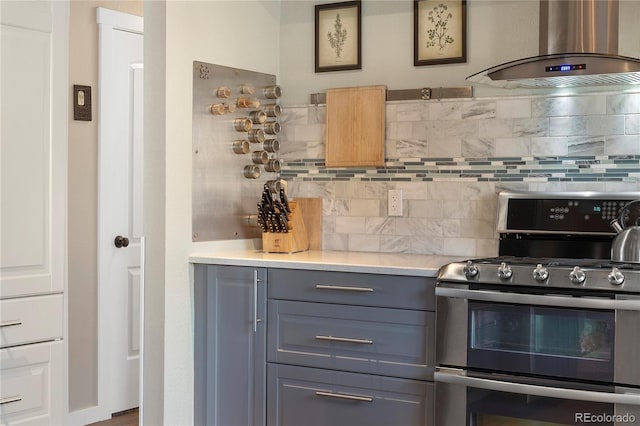 kitchen with tasteful backsplash, extractor fan, gray cabinets, and range with two ovens