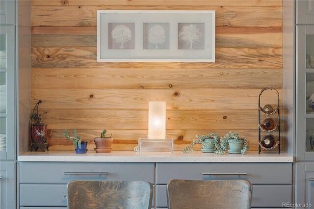 bar featuring wooden walls and gray cabinetry