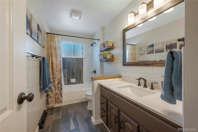 full bathroom featuring wood-type flooring, tile walls, vanity, shower / tub combo, and toilet