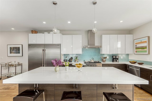 3168 W 29th Ave, Denver, CO 80211 - kitchen with wall chimney range hood, stainless steel appliances, modern cabinets, a breakfast bar area, and light countertops