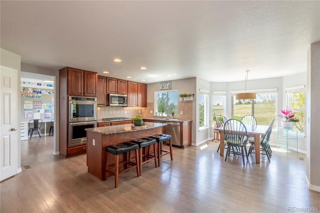 2339 Elkhorn St, Parker, CO 80138 - kitchen with stainless steel appliances, baseboards, a kitchen island, a breakfast bar area, and light wood-style floors