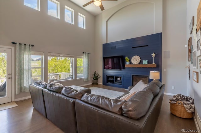 2339 Elkhorn St, Parker, CO 80138 - living area featuring wood finished floors, ceiling fan, a high ceiling, a glass covered fireplace, and baseboards