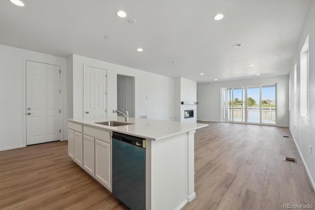 kitchen featuring sink, stainless steel dishwasher, an island with sink, and white cabinets