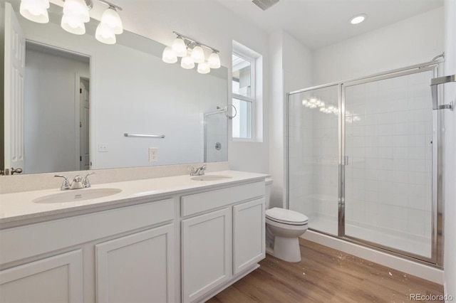 bathroom featuring vanity, toilet, wood-type flooring, and a shower with door