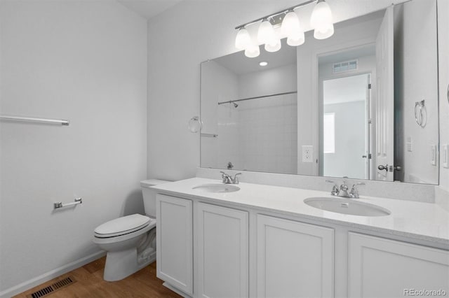 bathroom with toilet, a shower, vanity, and wood-type flooring