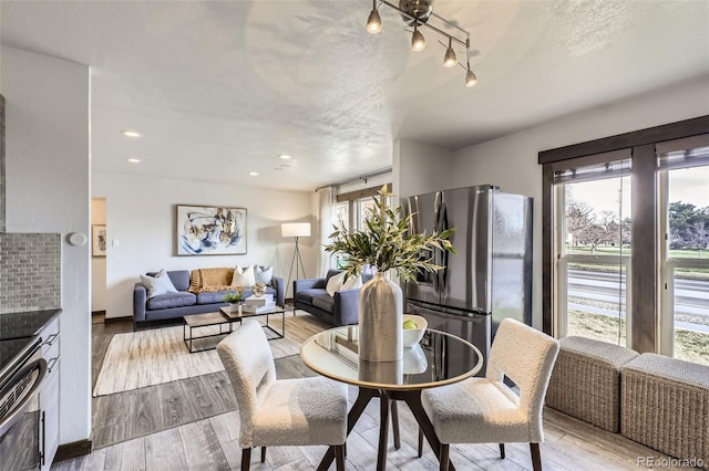 dining area with a textured ceiling and light hardwood / wood-style flooring