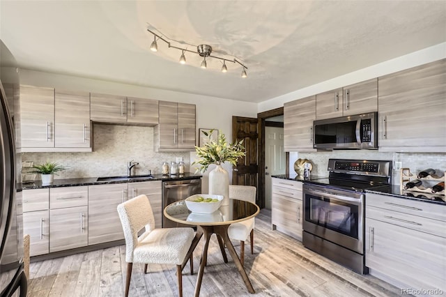 kitchen with backsplash, sink, light hardwood / wood-style floors, and appliances with stainless steel finishes