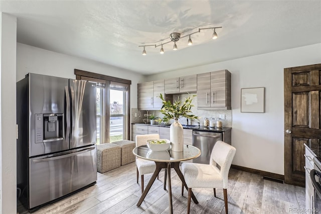 kitchen with backsplash, light hardwood / wood-style flooring, and appliances with stainless steel finishes